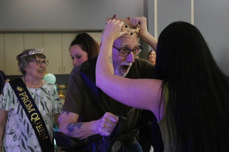 From left, Linda Hocker stands with her prom queen sash as Dennis Murray received his prom king crown. The two were selected as the prom king and queen for SageGrove at Raymore during the senior prom at Matt Ross Community Center.