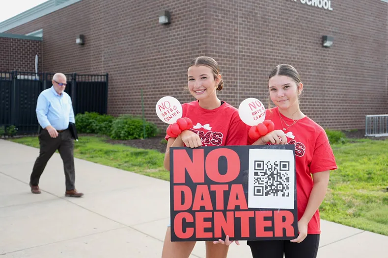 Erikah Sipes (left) and Bella Craig, both 14 years old, donned balloons on their wrists with anti-data center sentiments. The pair, who are getting ready to start their freshman year at De Soto High School, don’t want to attend school less than five miles from a data center.