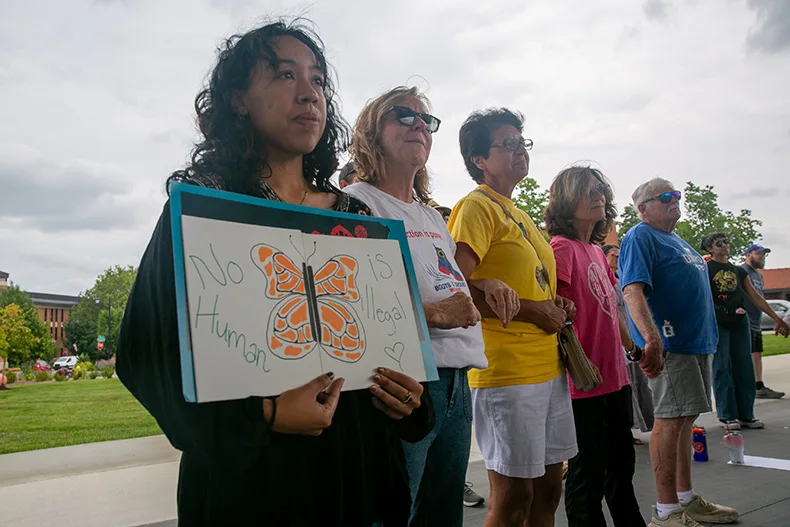 Nearly 100 people gathered at Johnson County Square Park to show support for Olathe's immigrant community amid recent ICE activity. Above, attendees lock arms. Photo credit Juliana Garcia.