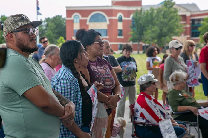 Nearly 100 people gathered at Johnson County Square Park to show support for Olathe's immigrant community amid recent ICE activity. Above, attendees listen to several speakers at the 