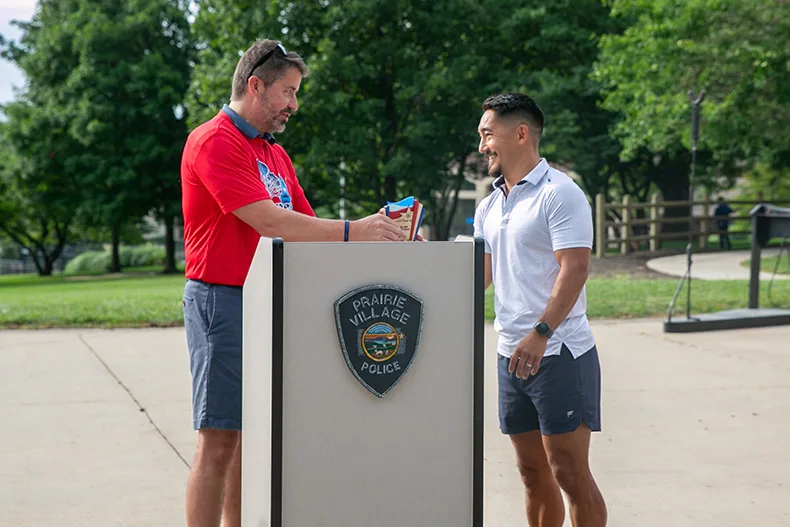 Mayor Eric Mikkelson presents resident Andrew Fujii with the 2026 community service award. Fujii fosters community in Prairie Village with a neighbor-led workout club, dubbed "Dad Bods." Photo credit Juliana Garcia. 