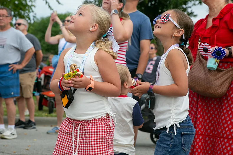 Two young girls are eager to catch candy at VillageFest 2026. Photo credit Juliana Garcia 