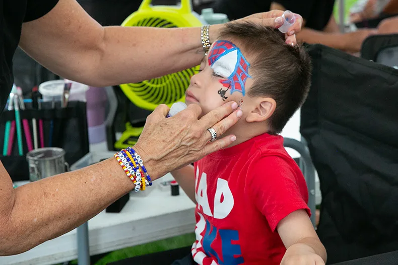 Despite the rain about two hours into the event, kids and parents packed the face painting, hair glittering and temporary tattoo booths. Above, a young boy gets a Spider-Man face painting. Photo credit Juliana Garcia. 