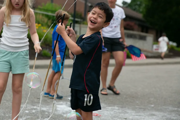 A young boy smiles after creating a large bubble at VillageFest 2026. Photo credit Juliana Garcia.