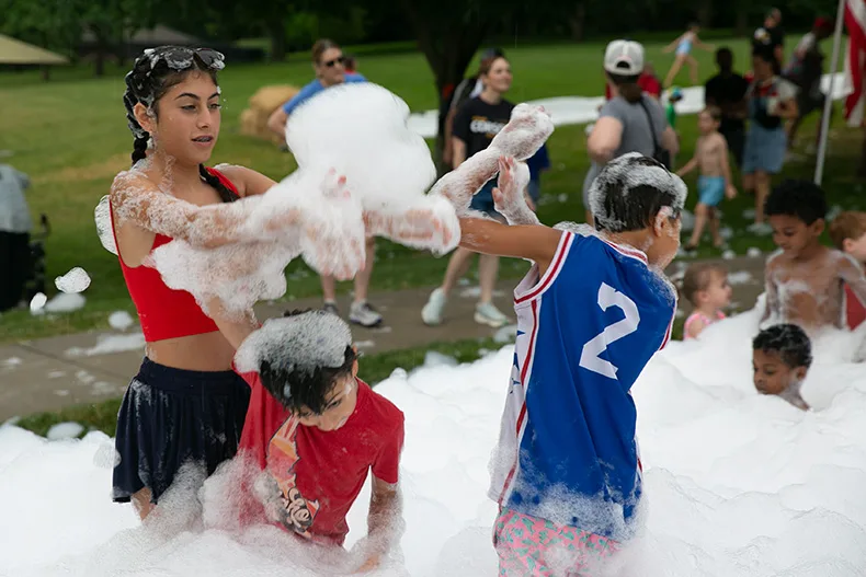 Two kids play in the foam party at VillageFest 2026, a new option for attendees. Photo credit Juliana Garcia.