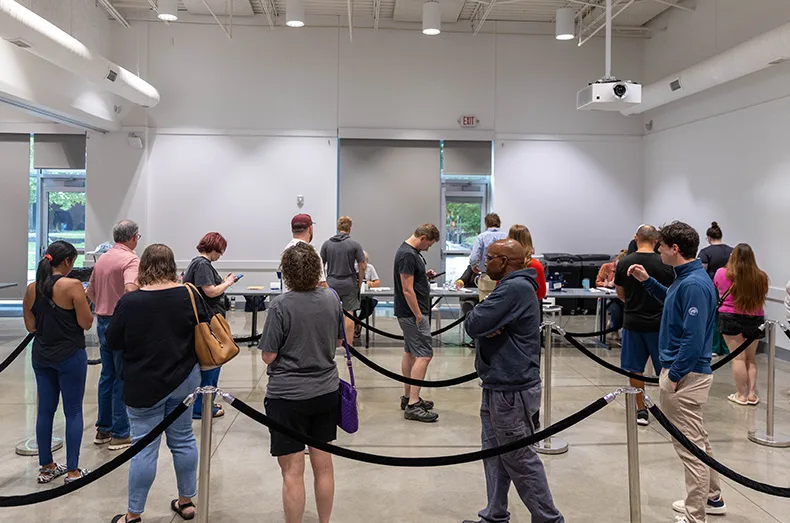 Voters wait in line inside the Johnson County Arts & Heritage Center in Overland Park to check in and cast their ballots on Tuesday, Aug. 4, 2026.