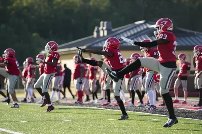 Football players from a Mississippi high school warm up before practice. There are new recommendations to get big linemen safe during hot weather workouts.