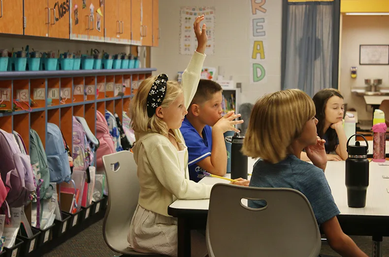 A third-grader raises her hand in class at Prairie Creek Elementary School.