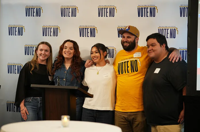 A group of friends pose for a photo in front of a “Vote No” background while at a watch party on Tuesday night for voters opposed to the constitutional amendment to elect Kansas Supreme Court justices.