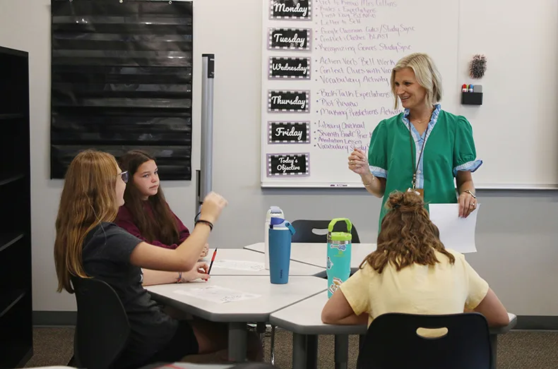 Students talk with a teacher during class at Woodland Springs Middle School.