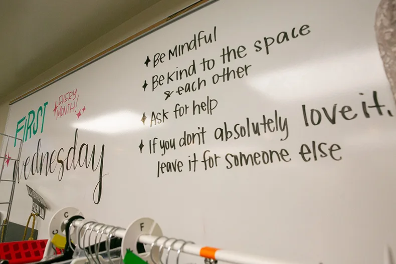 The whiteboard near the processing center of the Boutique reminds shoppers to "be mindful" and "ask for help," among other messages. Photo credit Juliana Garcia. 
