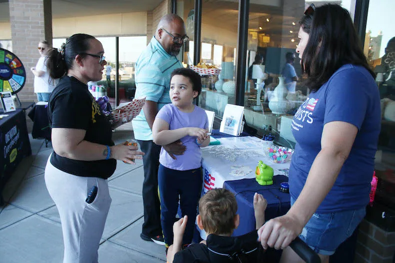 From left, Tara Patterson, Dakari Patterson and Jimmie Patterson talk with Logan Sabin and Melissa Sabin at the Alliance for a Healthy Kansas "One Nation, Overcharged" event at Rosanna Square on Thursday, Aug. 27.