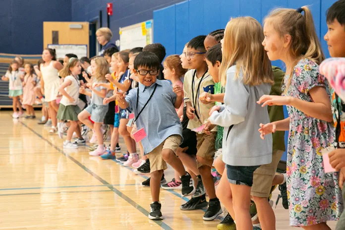 First grade students at Pawnee Elementary hop around on one foot during Simon Says in the gym on the first day of school. Photo credit Juliana Garcia.