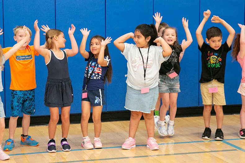 First grade students put their hands up to follow the instructions during a game of Simon Says. Photo credit Juliana Garcia.