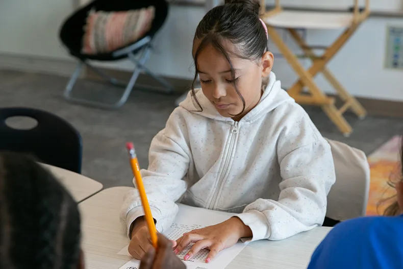 Students worked on small projects on the Aug. 12, 2026, for their first day back. Above, a third grade girl writes her name on the top of a word search worksheet. Photo credit Juliana Garcia.