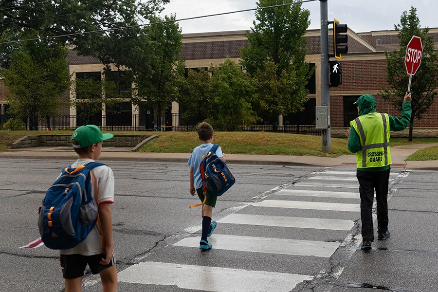 Crossing guard Terry Friedrich helps Brookwood Elementary students cross 103rd Street on the morning of Thursday, Sept. 10.