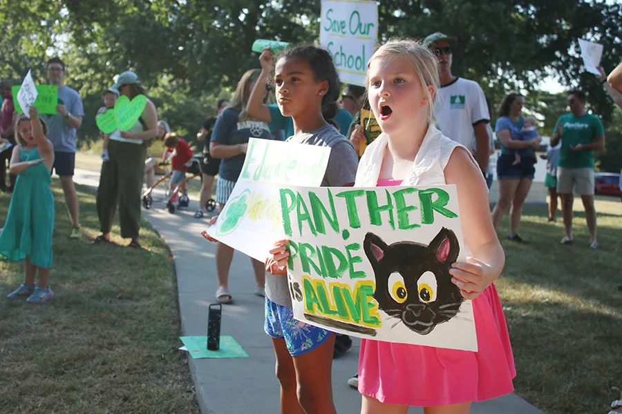 From left, Presley Carr, 9, and Keira Riederer, 9, show their support for East Antioch Elementary during a rally along 71st Street in Merriam Sept. 1.