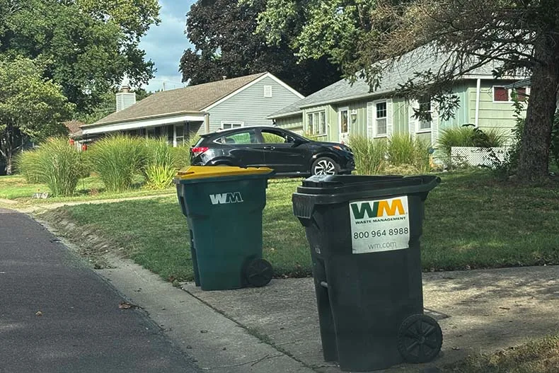 A trash bin and a recycling bin sit at the end of a northern Overland Park driveway ahead of trash pickup day.