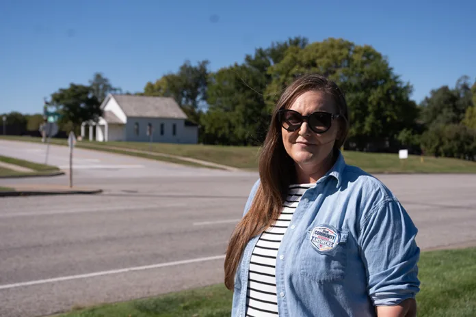Walnut Grove parent Gera Netcher, co-founder of Olathe Families United, stands across the street Oct. 2 from the school and its historic one-room school house. She's hoping to get the Kansas State Board of Education to review the closures. Photo credit Margaret Mellott.