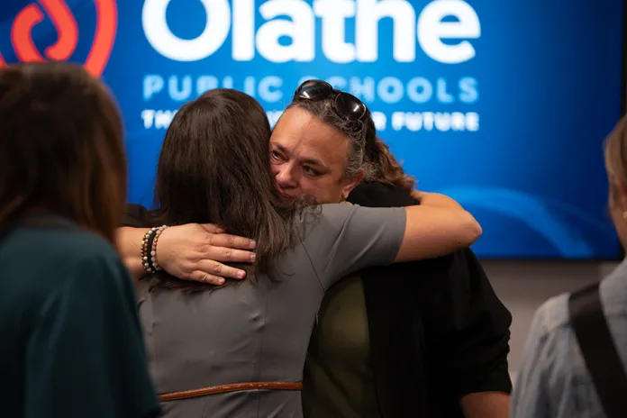 Black Bob parent Hannah Jeffrey embraces Olathe Board of Education member Claire Reagan after Thursday night's meeting, during which the board unanimously voted to close six schools, including Black Bob, at the end of the 2026-27 school year. Photo credit Margaret Mellott.