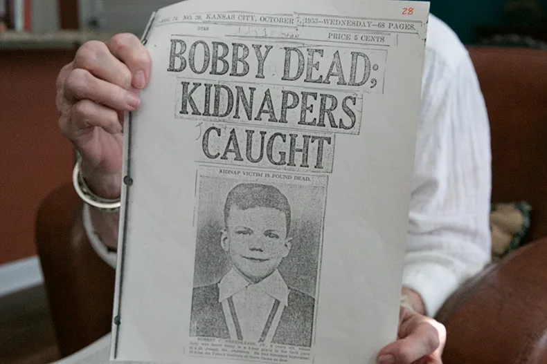 Melinda Worth Popham holds a scanned copy of a newspaper with a headline that reads "Bobby Dead; Kidnappers Caught." Photo credit Juliana Garcia.